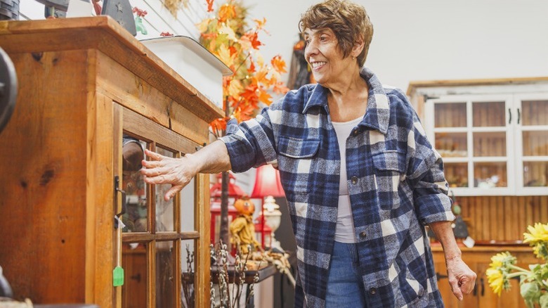 woman inspecting wood cabinet construction in thrift store