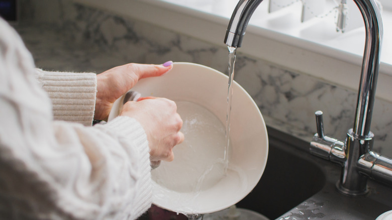 A person doing dishes at the kitchen sink