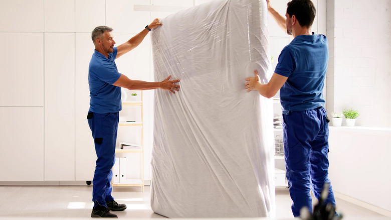 Two men moving a mattress in a home.