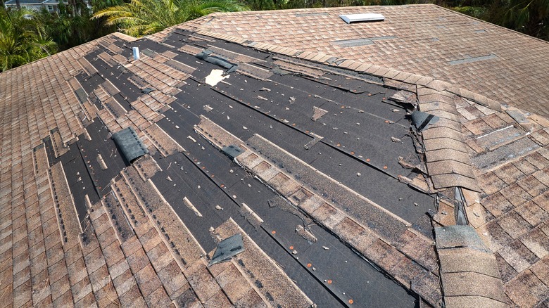 A roof with storm damage missing some shingles