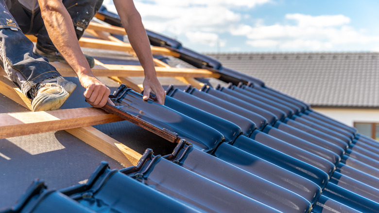 Person installing shingles on roof