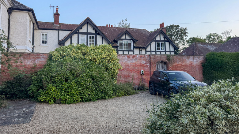 Gravel driveway with red brick wall and white house behind