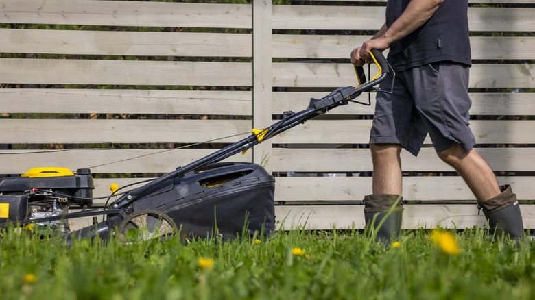 Man wearing boots and mowing the lawn
