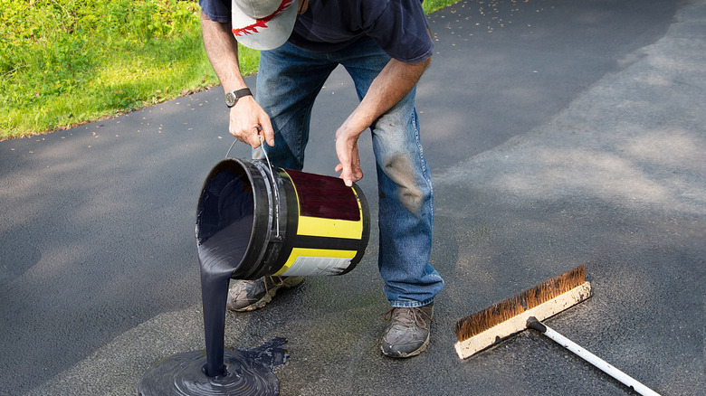 Person pouring sealant on driveway