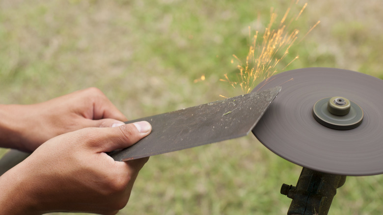 Person sharpening a mower blade