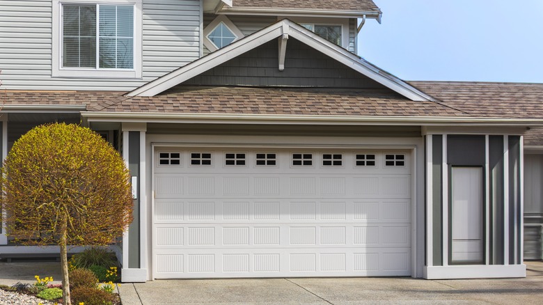 A garage with white doors attached to a modern house