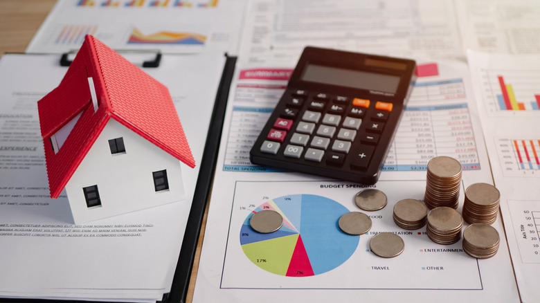 Calculator, coins, toy house, and data reports on desk