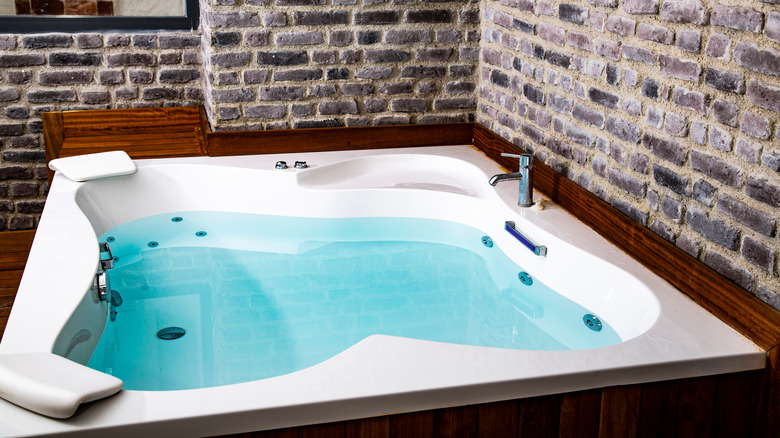 Jacuzzi tub with brick wall 