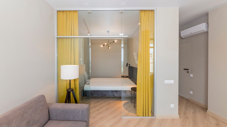 A den converted into a bedroom with yellow curtains as partitions