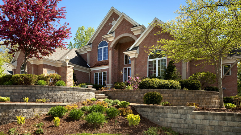 a brick mansion with tiered retaining walls in the landscaping