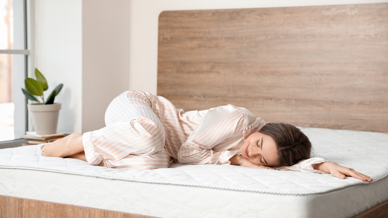 Woman lying on uncovered mattress