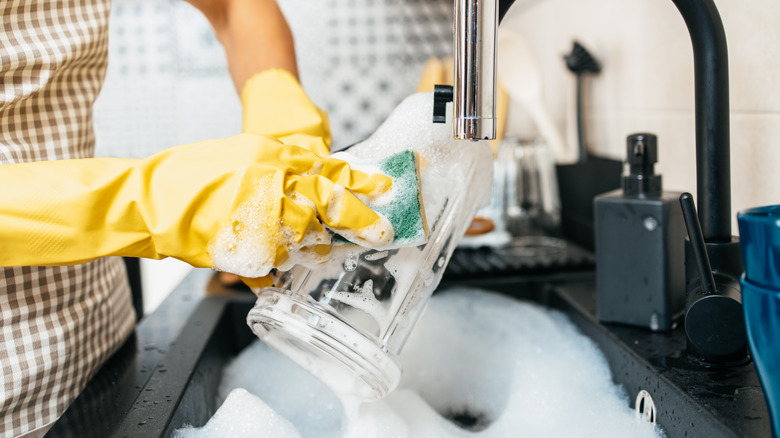 Person with gloves hand-washing dishes