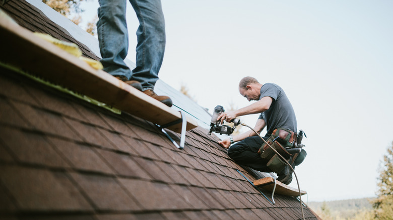 Workers installing shingles on a roof