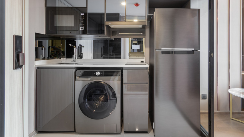 A series of stainless steel appliances including a dishwasher, fridge, washer, and microwave