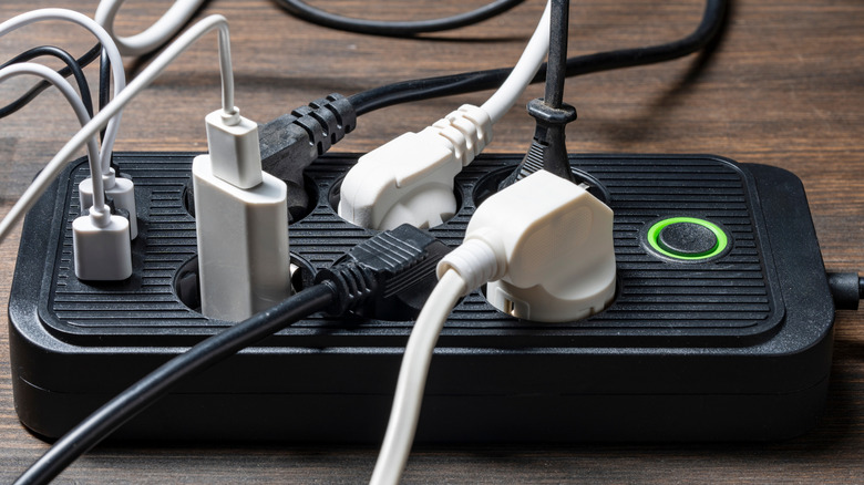 A power strip with an on and off button fully filled with regular AC power cords and USB chargers