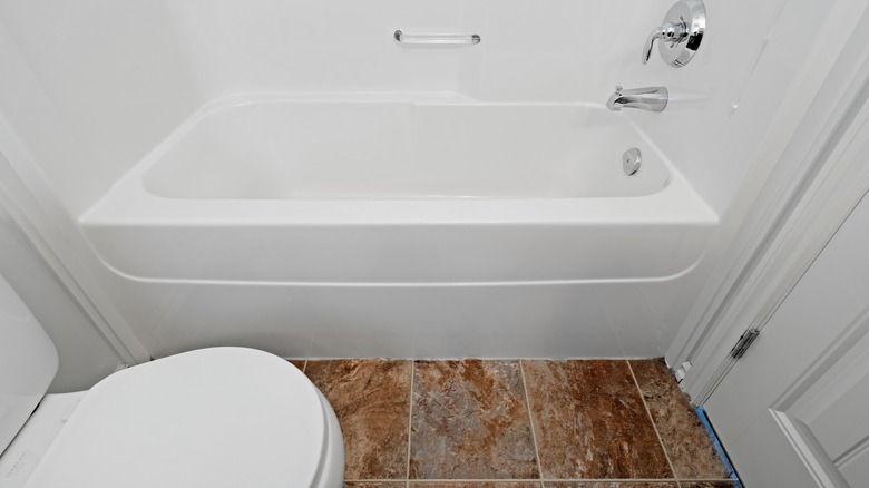 Bathroom with white bathtub and colored tile flooring.
