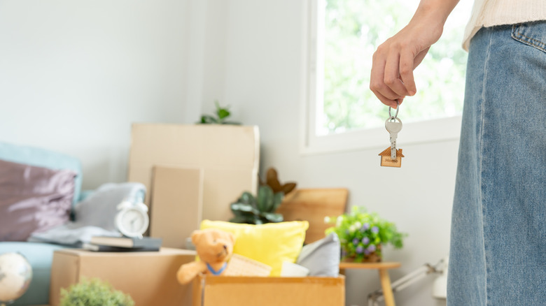 person holding keys standing near packing boxes