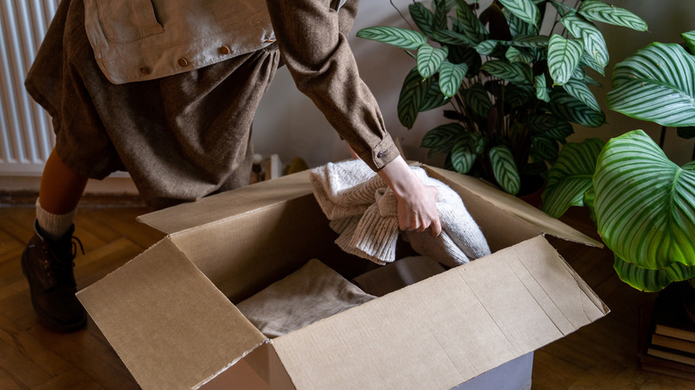 Woman putting a sweater in a cardboard box