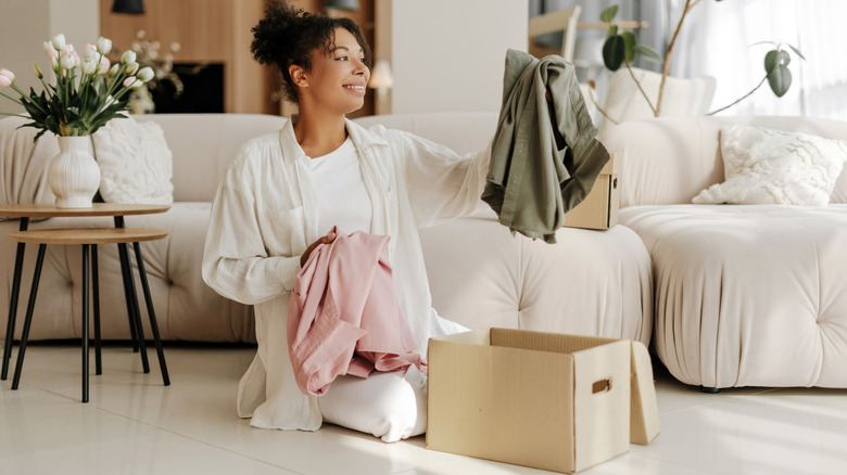 Woman looking at two shirts with a cardboard box lying open in front of her