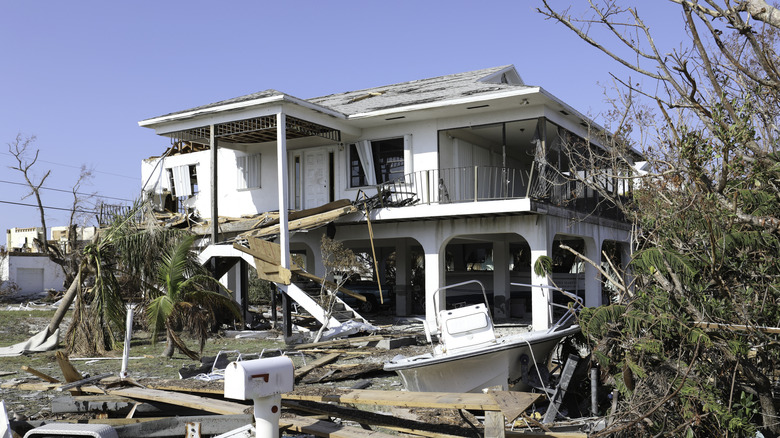 home that was affected by hurricane with major damage and debris outside