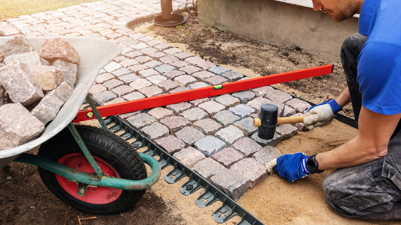 man installing cobbled stone path by hand