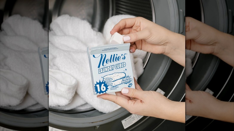 Hand preparing to throw a Nellie's laundry cube into the washer.
