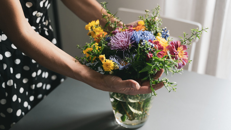 Woman holding vase with fresh cut flowers 