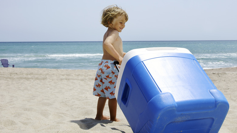 Child carrying cooler at the beach