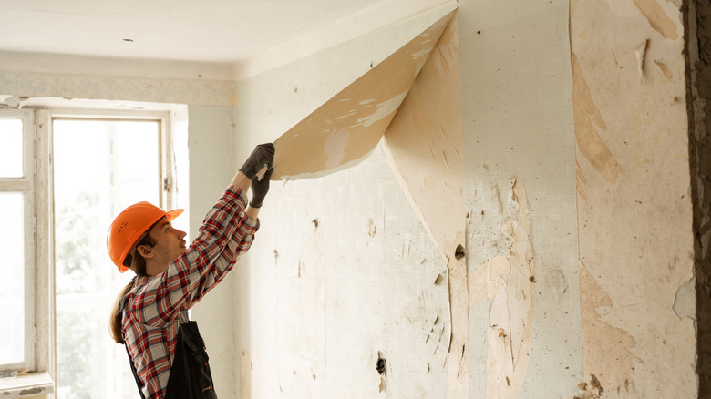 Man peeling off wallpaper from wall