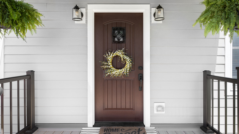 A light gray house with white trim and a dark brown door that matches the railings