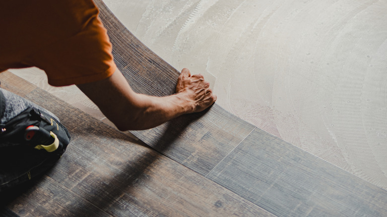 Man installing luxury vinyl plank flooring over concrete