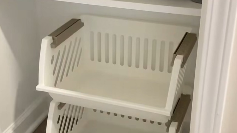 Linen closet with stackable white baskets on the floor level.