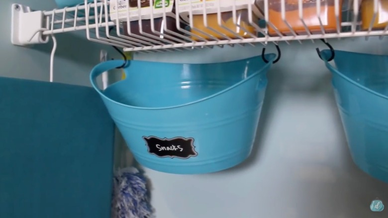 Laundry room pantry combo with blue plastic buckets hanging from hooks under wire shelves.