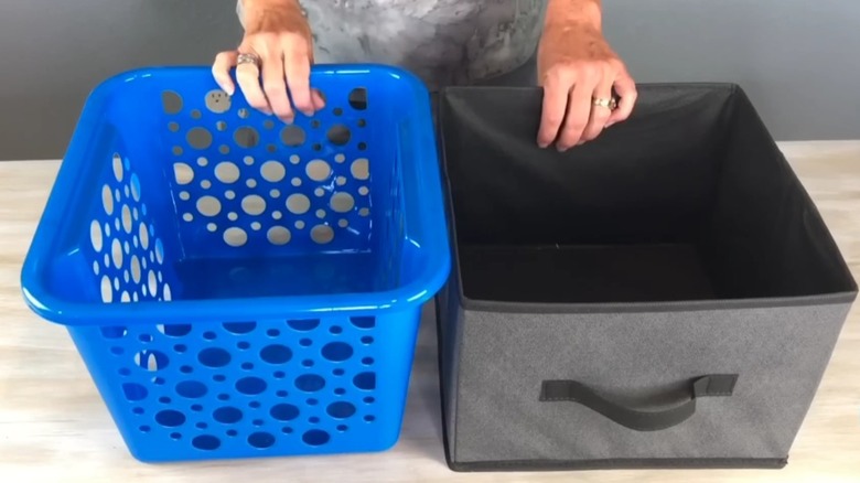 A blue dollar store basket inside of a gray fabric storage cube used to store rolls of shirts and socks.