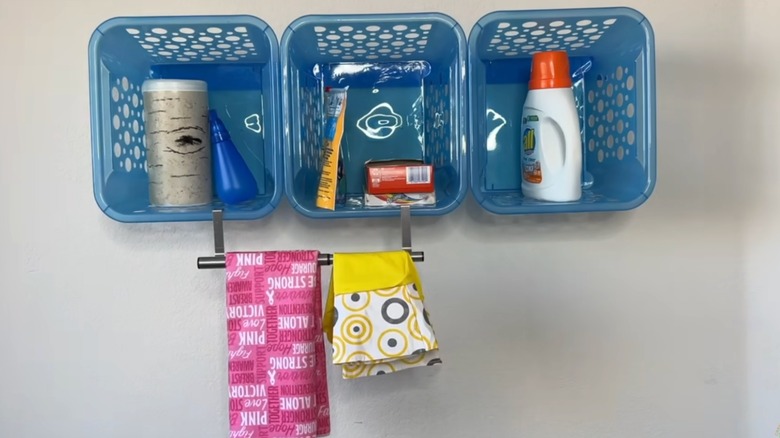Screenshot of YouTube video, showing three blue Dollar Tree baskets used as laundry room wall shelves.