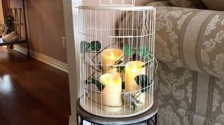 A finished birdcage-inspired farmhouse decor, created from cooling racks from the Dollar Tree, sits on a side table in the living room.