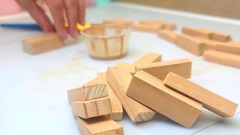 Close-up of a wood pieces from a board game with a person's hand int he background holding one piece
