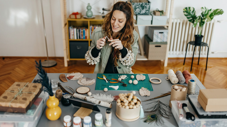 A woman works on a DIY project at a table