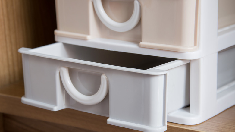A set of small stackable plastic drawers in a wooden cabinet