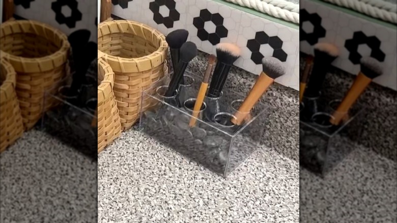 A Dollar Tree plastic flower vase filled with rocks turned into a DIY makeup brush holder.