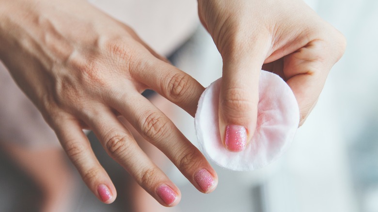 Close-up of person removing nail polish with cotton pad