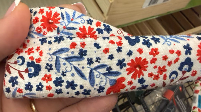 A person holds up red, white and blue floral craft fabric inside a Dollar Tree store