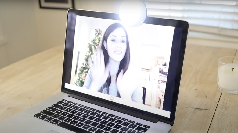 A push light is clipped to the top of the computer screen to brighten the person for the video