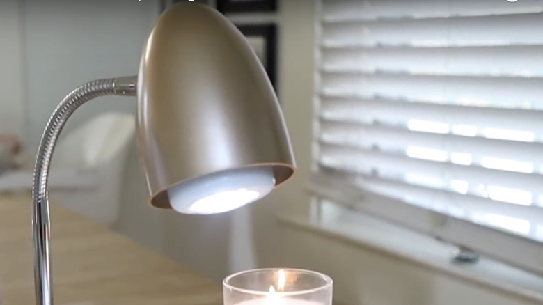 The DIY desk lamp sits on a desk with a candle.
