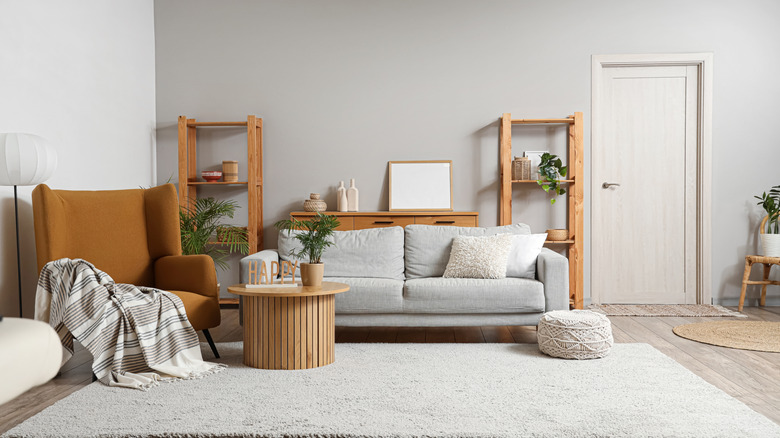 Interior of stylish living room with a brown armchair, gray sofa, and wooden coffee table; no storage tray is present.