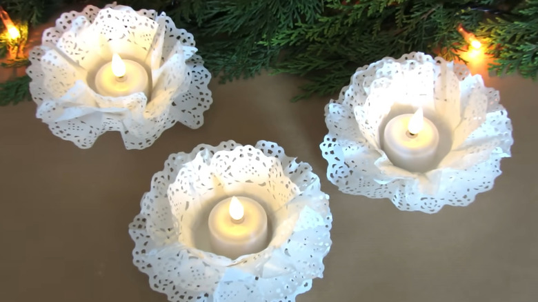 Three tea light candles in DIY candleholders made out of paper doilies