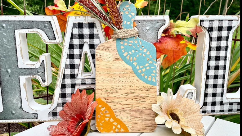 Small wood cutting board with paper doilies decoupaged onto it and florals on the top