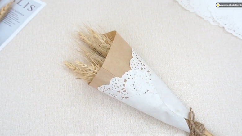 Dried florals wrapped in a brown paper cone decorated with a white paper doily