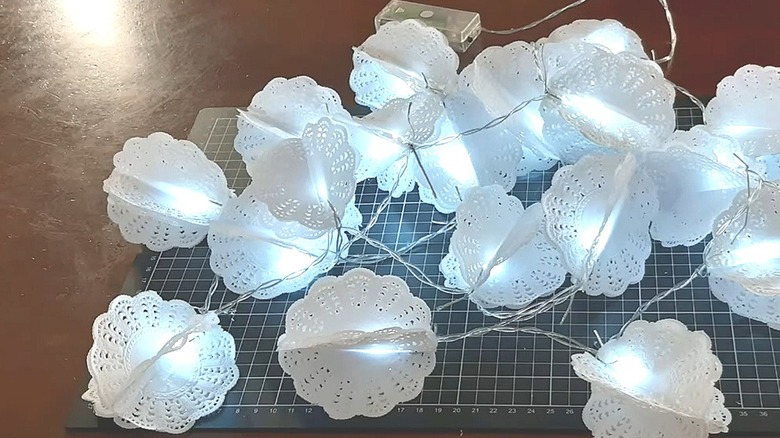 Strand of battery-powered lights with small paper doily designs covering them