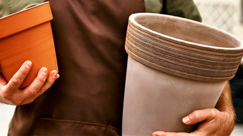 Close-up of a person holding two empty planter pots